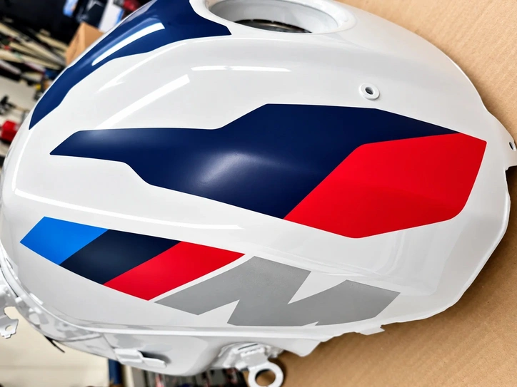 Weiße Motorradverkleidung mit mehrfarbiger Folierung in Blau, Rot, Schwarz und Silber