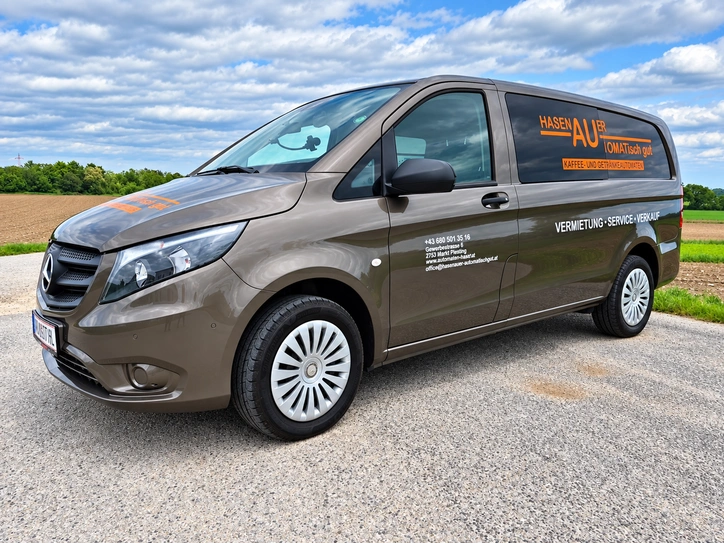 Brauner Transporter mit orange-weißer Firmenbeschriftung, Logo, Kontaktdaten und Servicehinweisen.