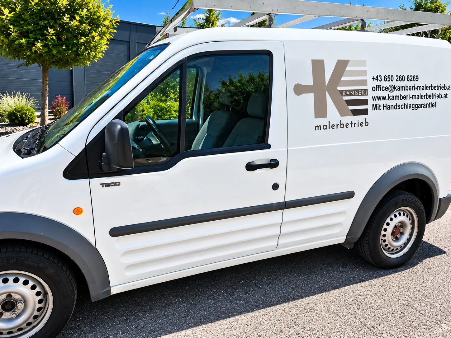 Weißer Firmenwagen mit professioneller Beschriftung, Firmenlogo und Kontaktdaten vor modernem Gebäude.