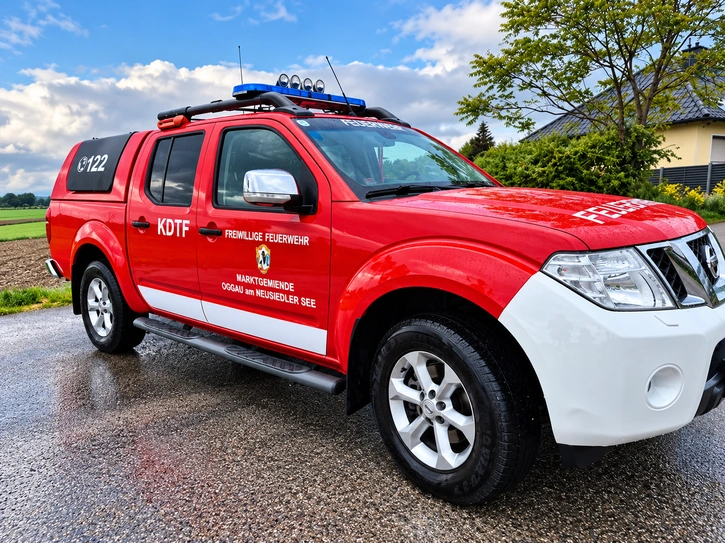 Rot-weißes Feuerwehrfahrzeug mit professioneller Beschriftung, Schriftzügen und Wappen.