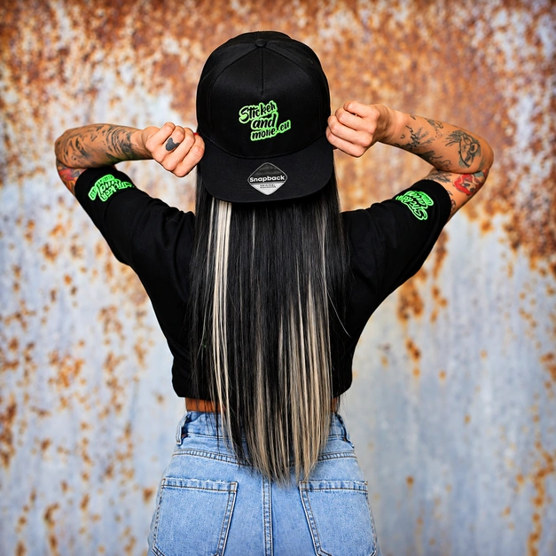 Schwarzes T-Shirt und Snapback-Kappe mit grünem Firmenlogo als individuelle Firmenbekleidung.
