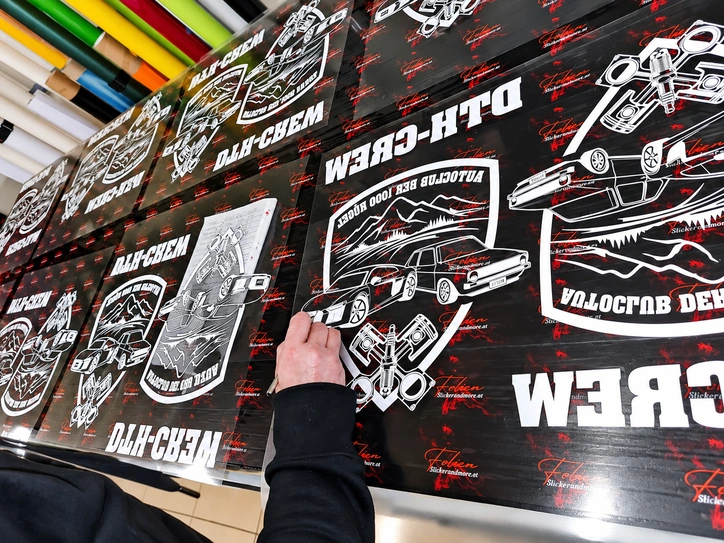 Textildruck-Motive mit Fahrzeugen, Motorsportgrafiken und Schriftzügen bei der Verarbeitung.