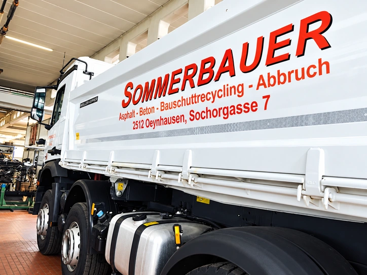 Weißer LKW mit auffälliger roter Firmenbeschriftung für Recycling, Asphalt, Beton und Abbruch.
