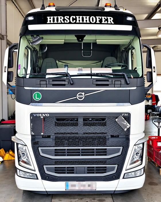 Frontansicht eines weißen Volvo FH mit gut sichtbarer Firmenbeschriftung oberhalb der Windschutzscheibe.